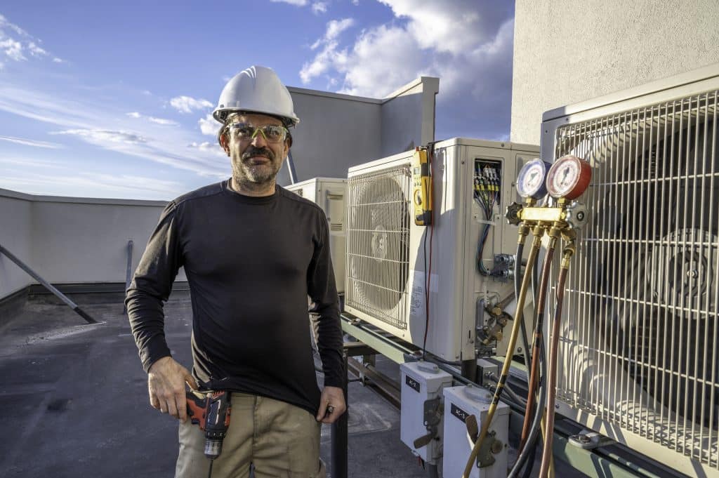 HVAC technician standing next to mini split ac's