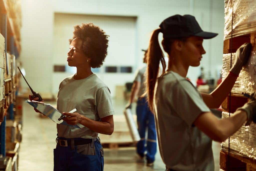 African American warehouse dispatcher checking stock in industrial storage compartment.